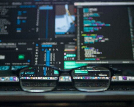Computer code visible through glasses on a laptop
